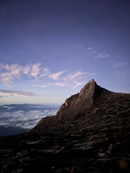 a very tall mountain with some clouds in the sky