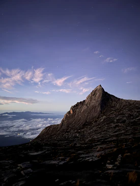 a very tall mountain with some clouds in the sky