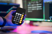 a person holding a remote control in front of a computer