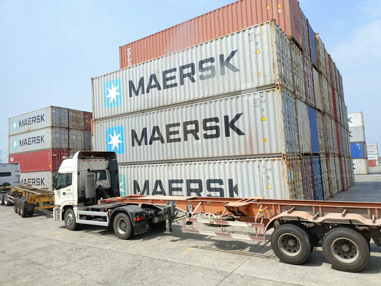 Semi-trailer truck parked next to a shipping container