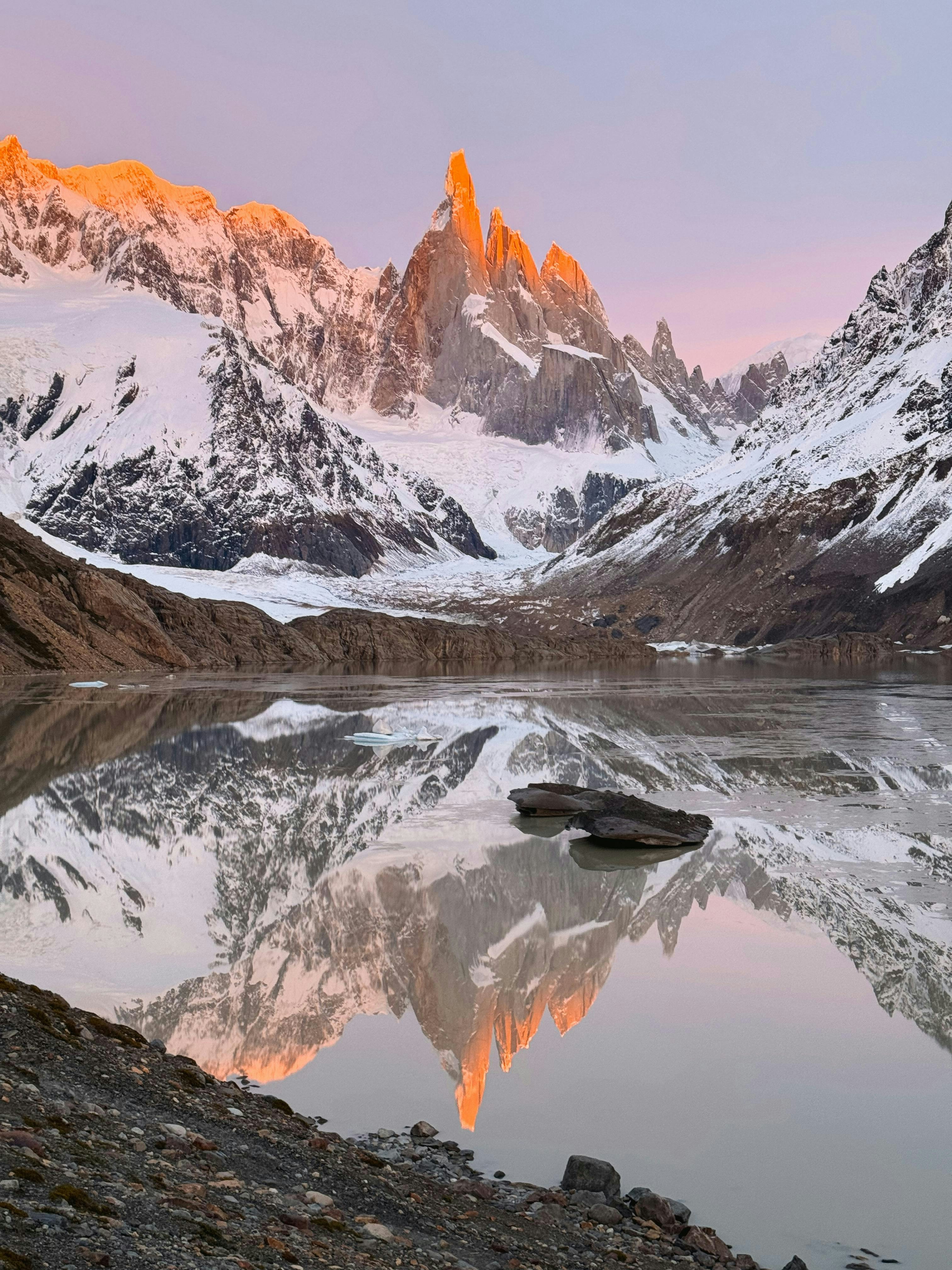 a mountain range is reflected in the still water of a lake