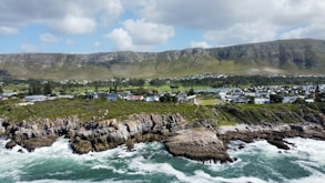 a scenic view of the ocean with houses and mountains in the background