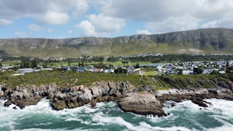 a scenic view of the ocean with houses and mountains in the background