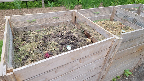 Две дървени градински клетки, пълни с компост и мулч за подобряване на почвата и грижа за градината.