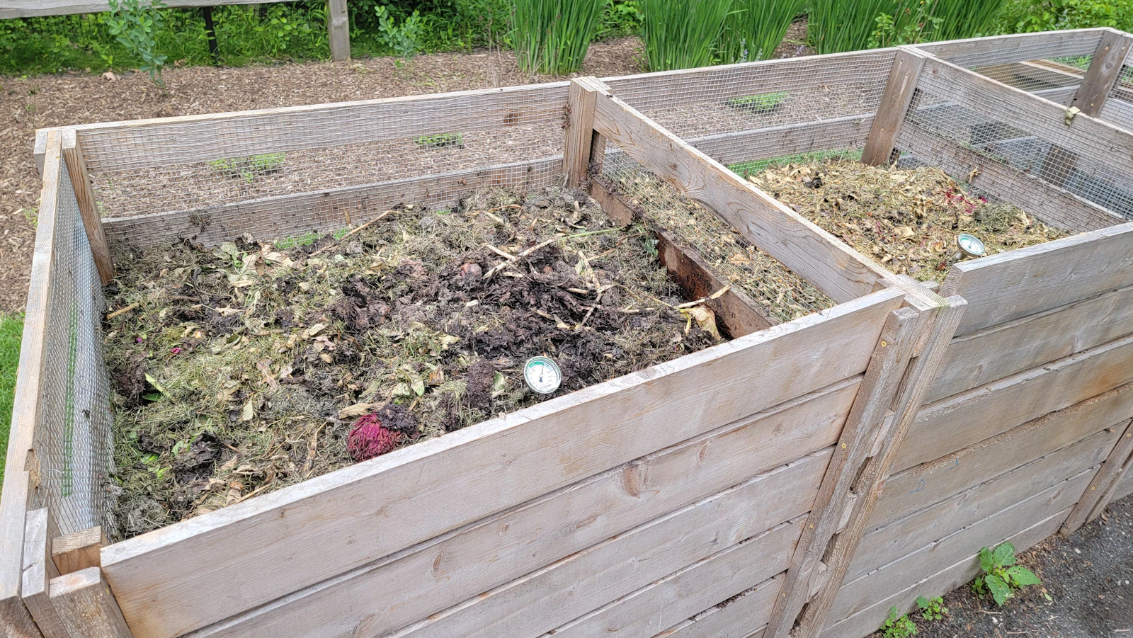 Wooden compost bin boxes filled with soil in a garden