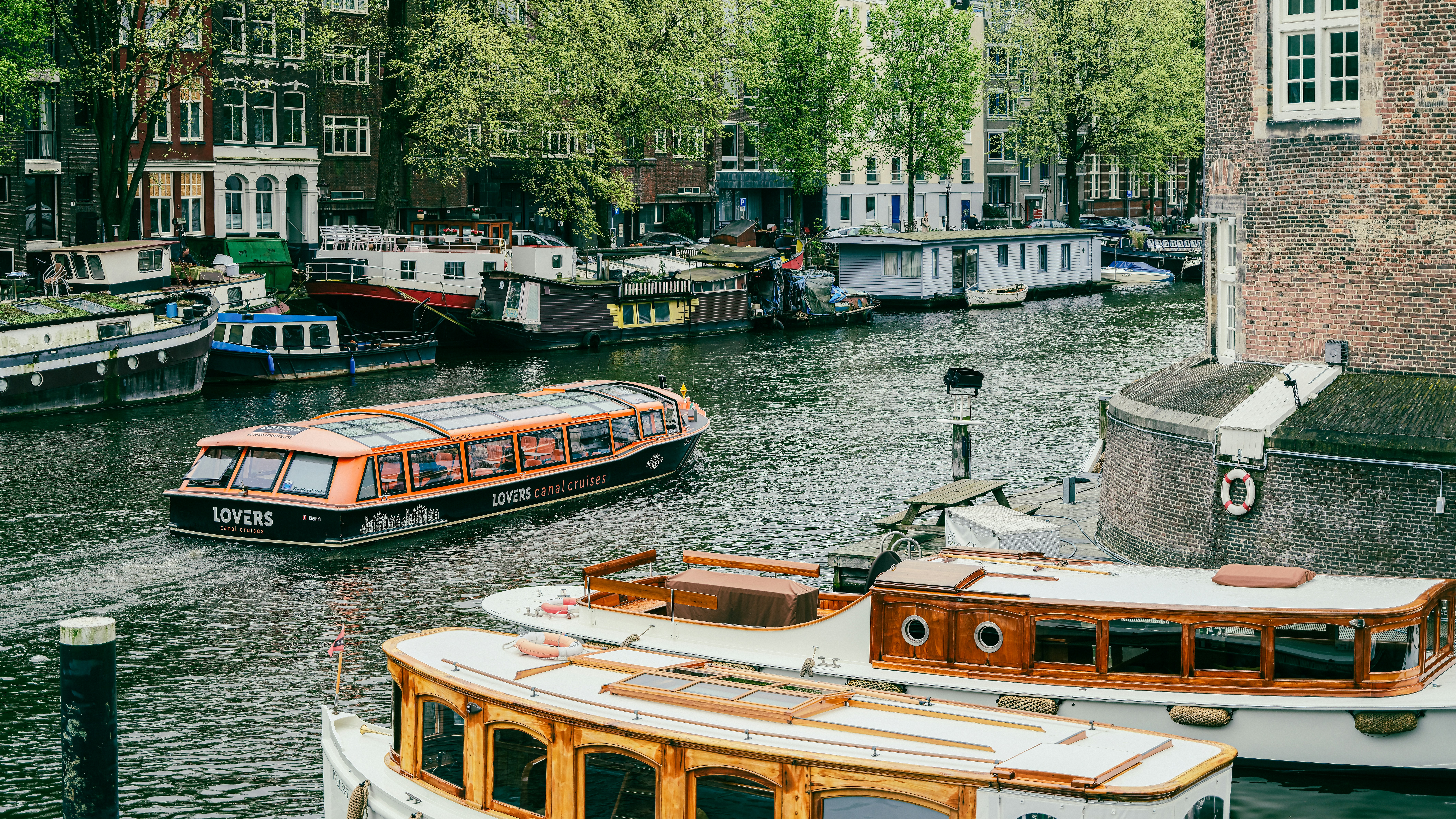 a river filled with lots of boats next to tall buildings
