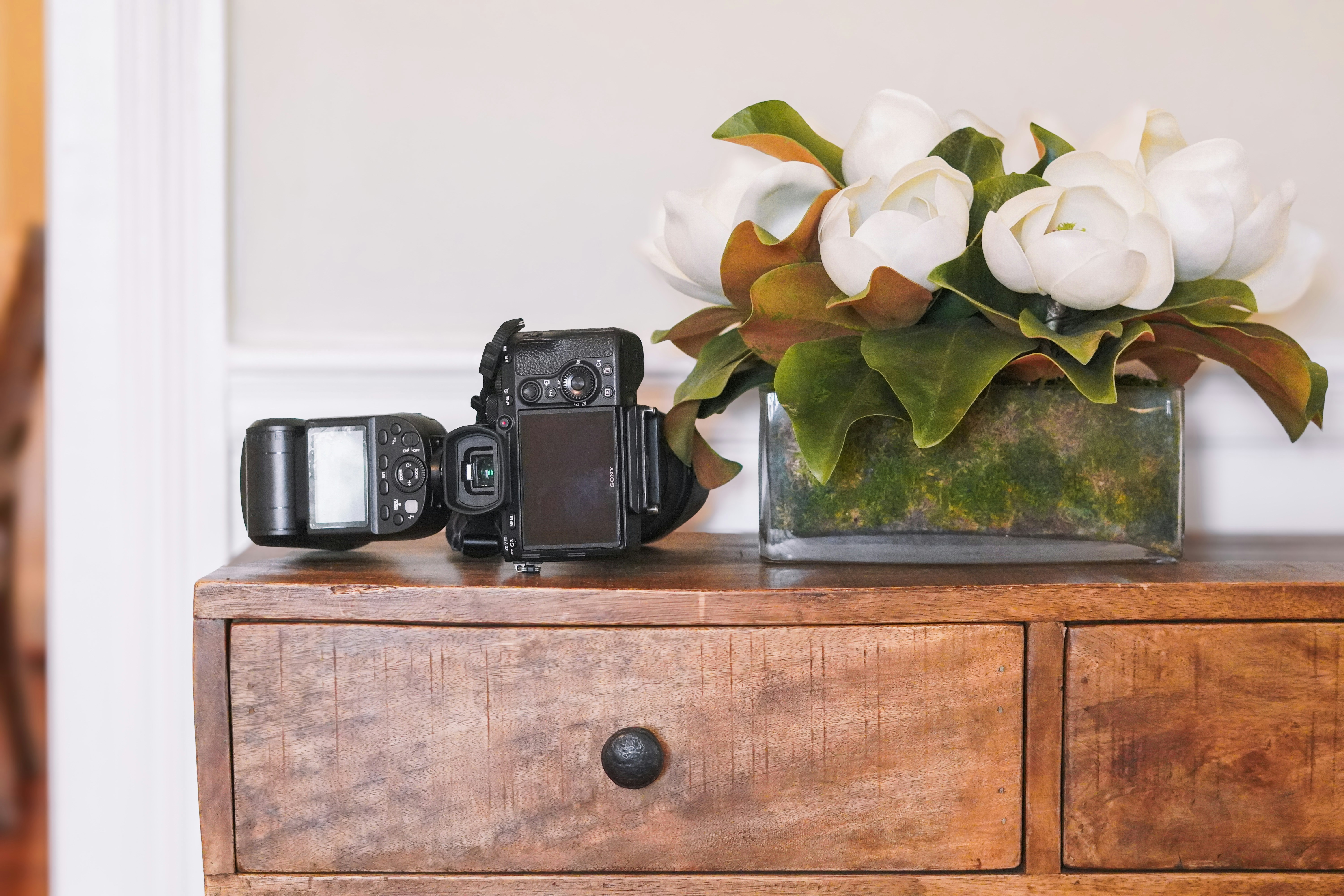 a wooden dresser topped with a vase filled with white flowers