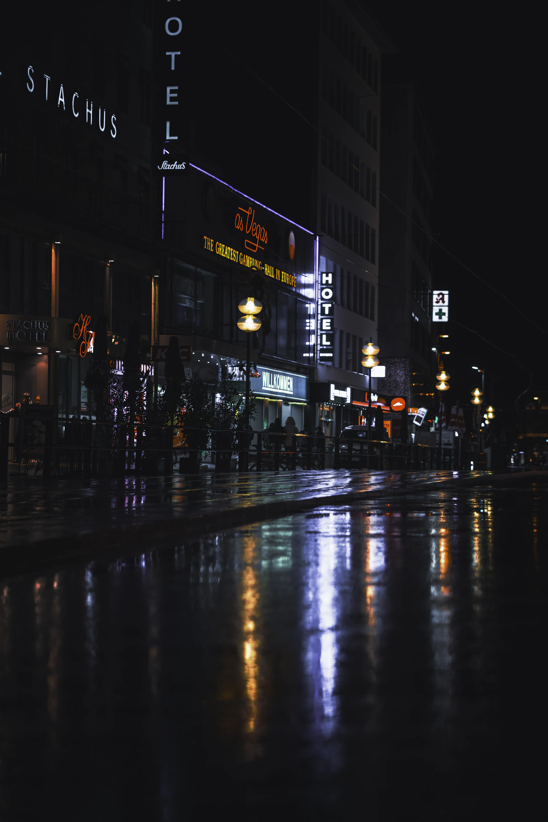 a city street at night with people walking on the sidewalk