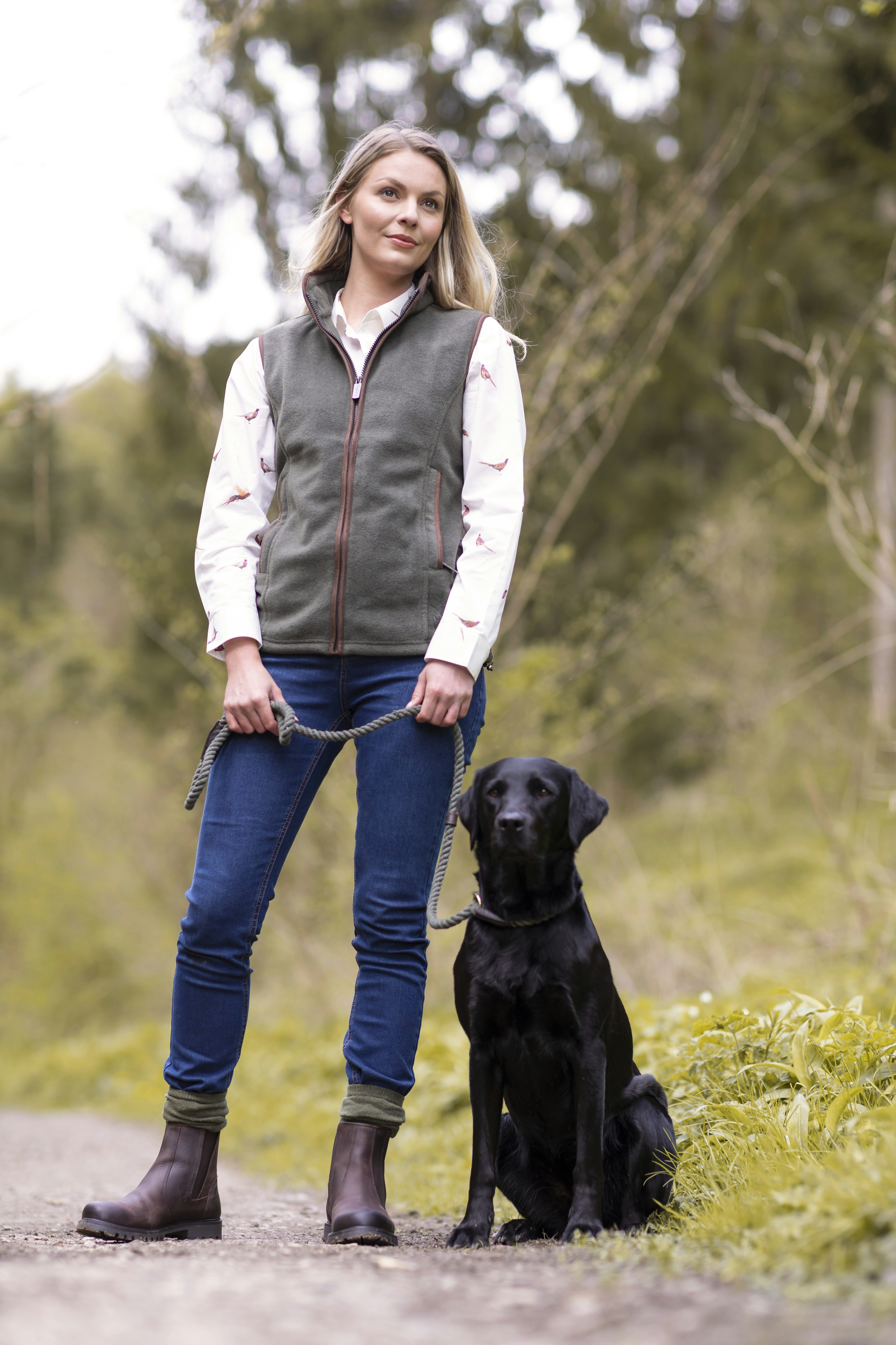 une femme debout à côté d’un chien noir