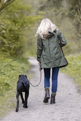 a woman walking a dog down a dirt road