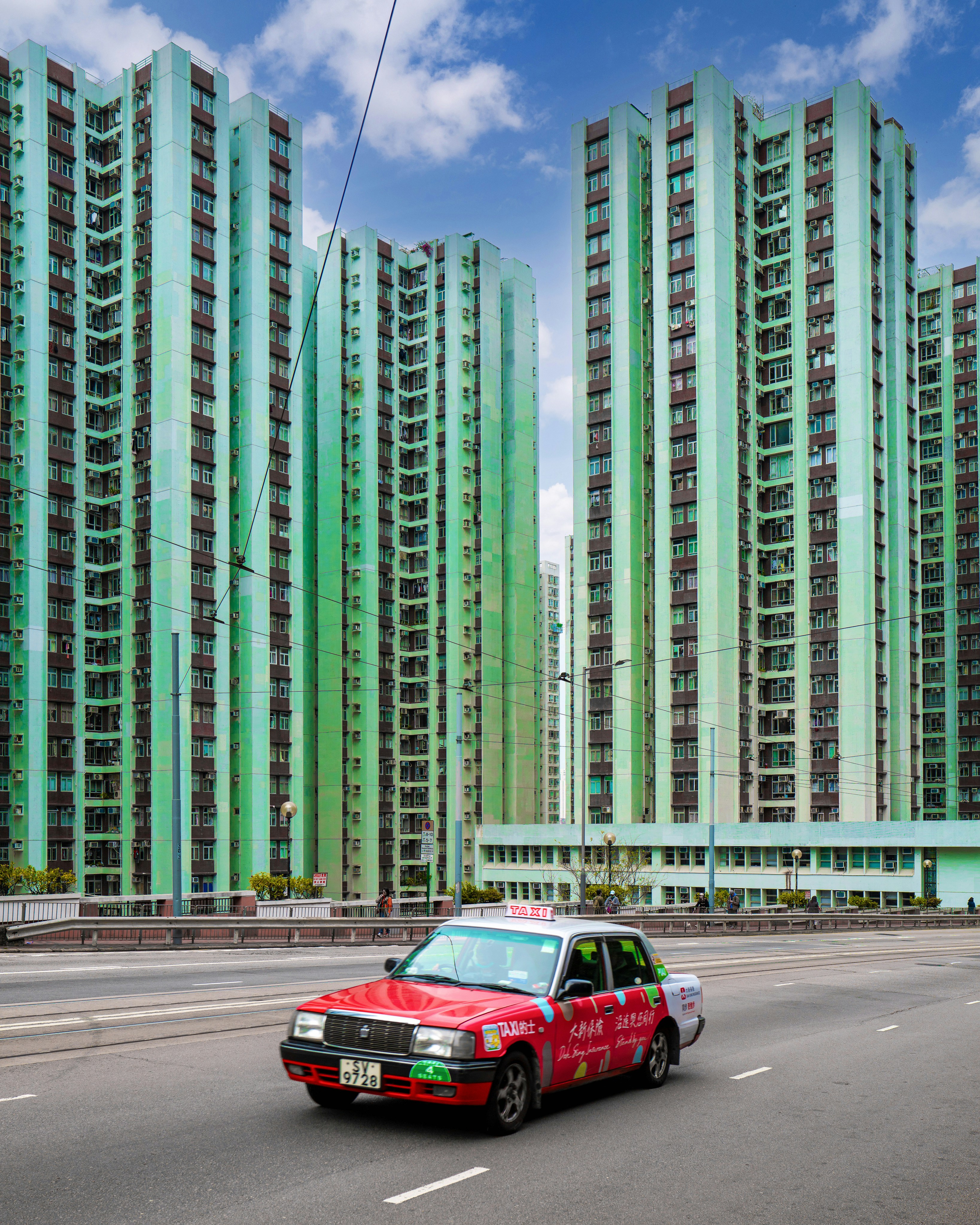 a red car driving down a street next to tall buildings