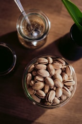 a glass bowl filled with nuts next to a cup of coffee