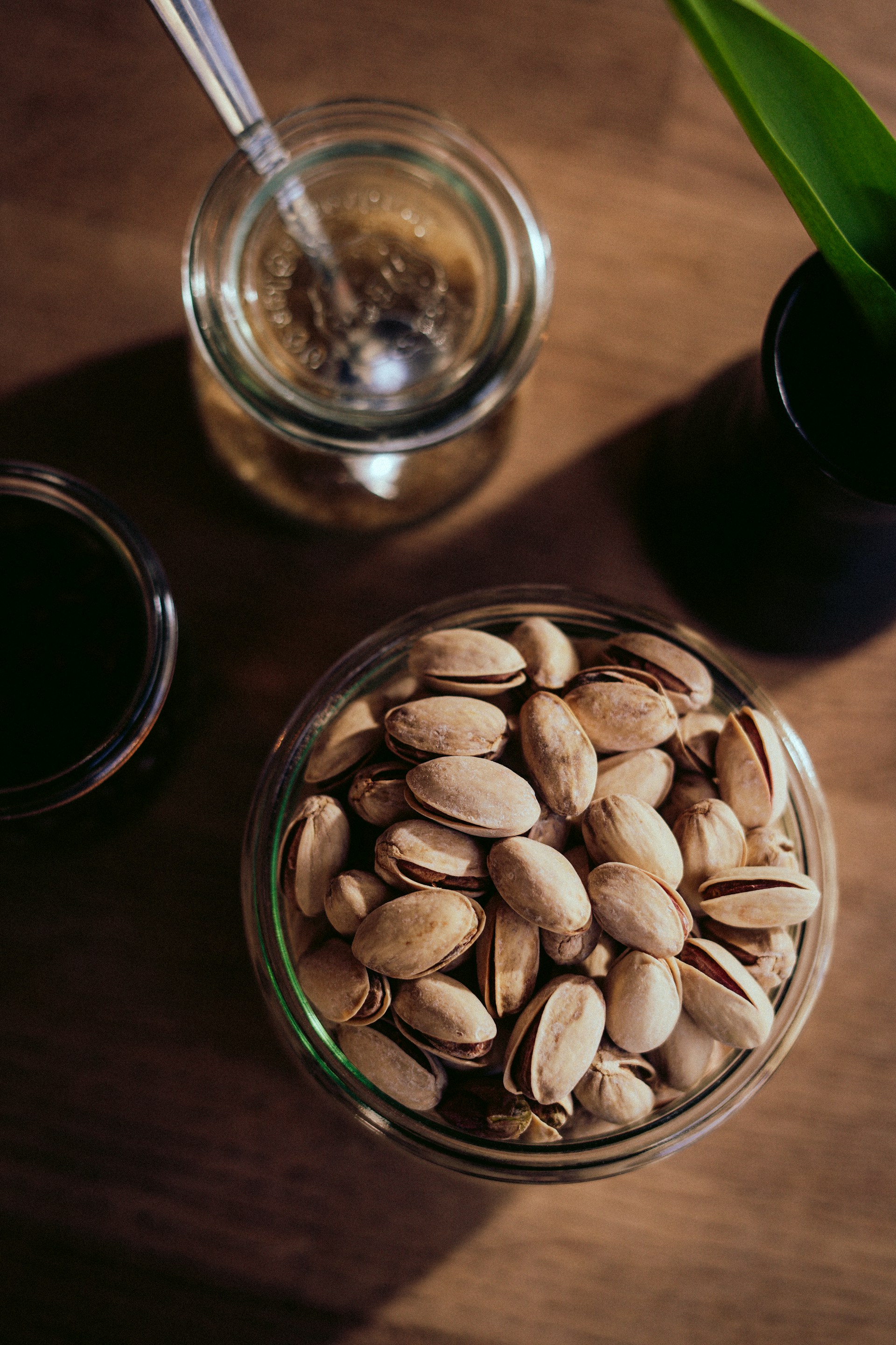 a glass bowl filled with nuts next to a cup of coffee
