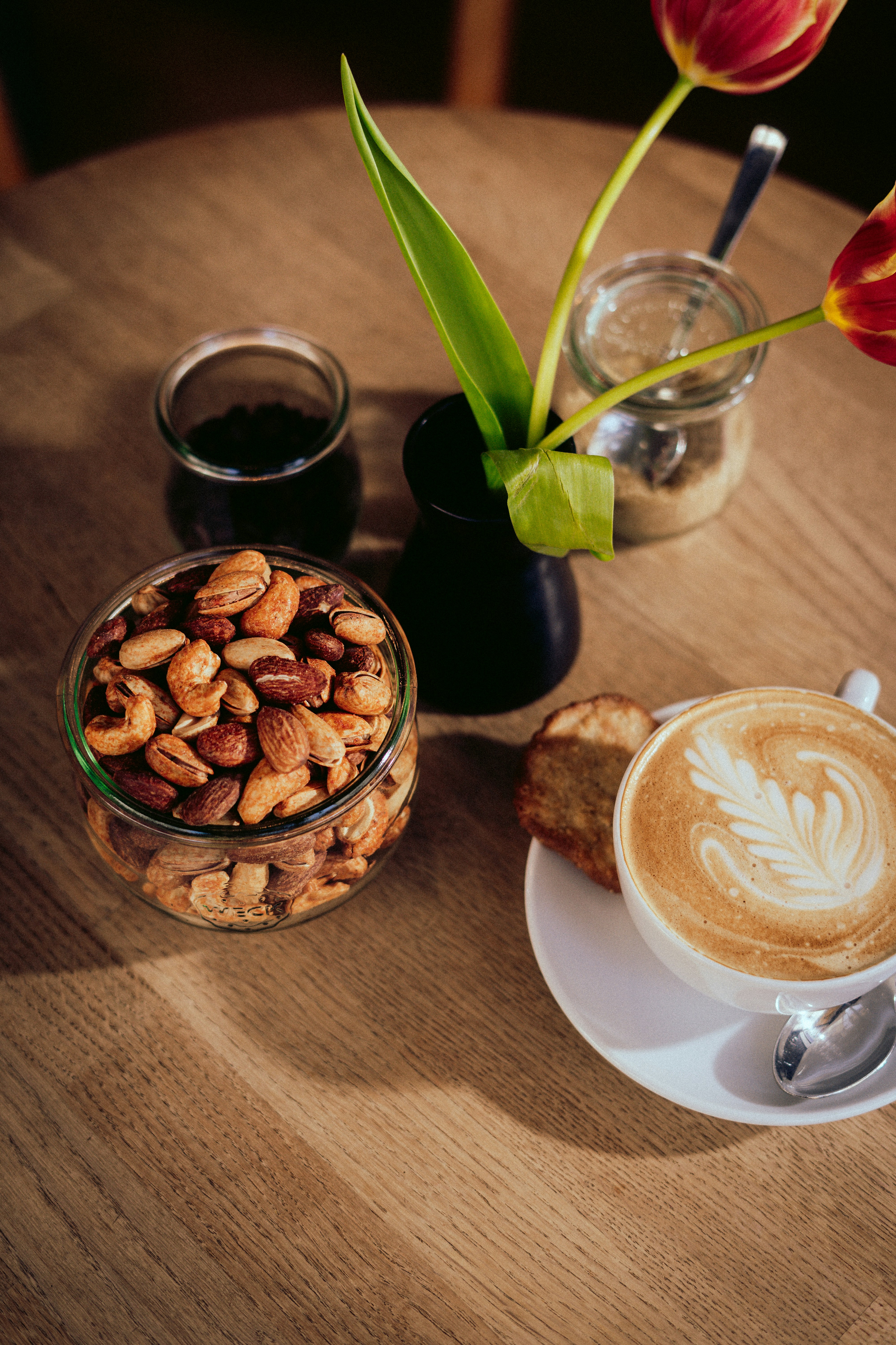 a table topped with a cup of coffee and a bowl of nuts