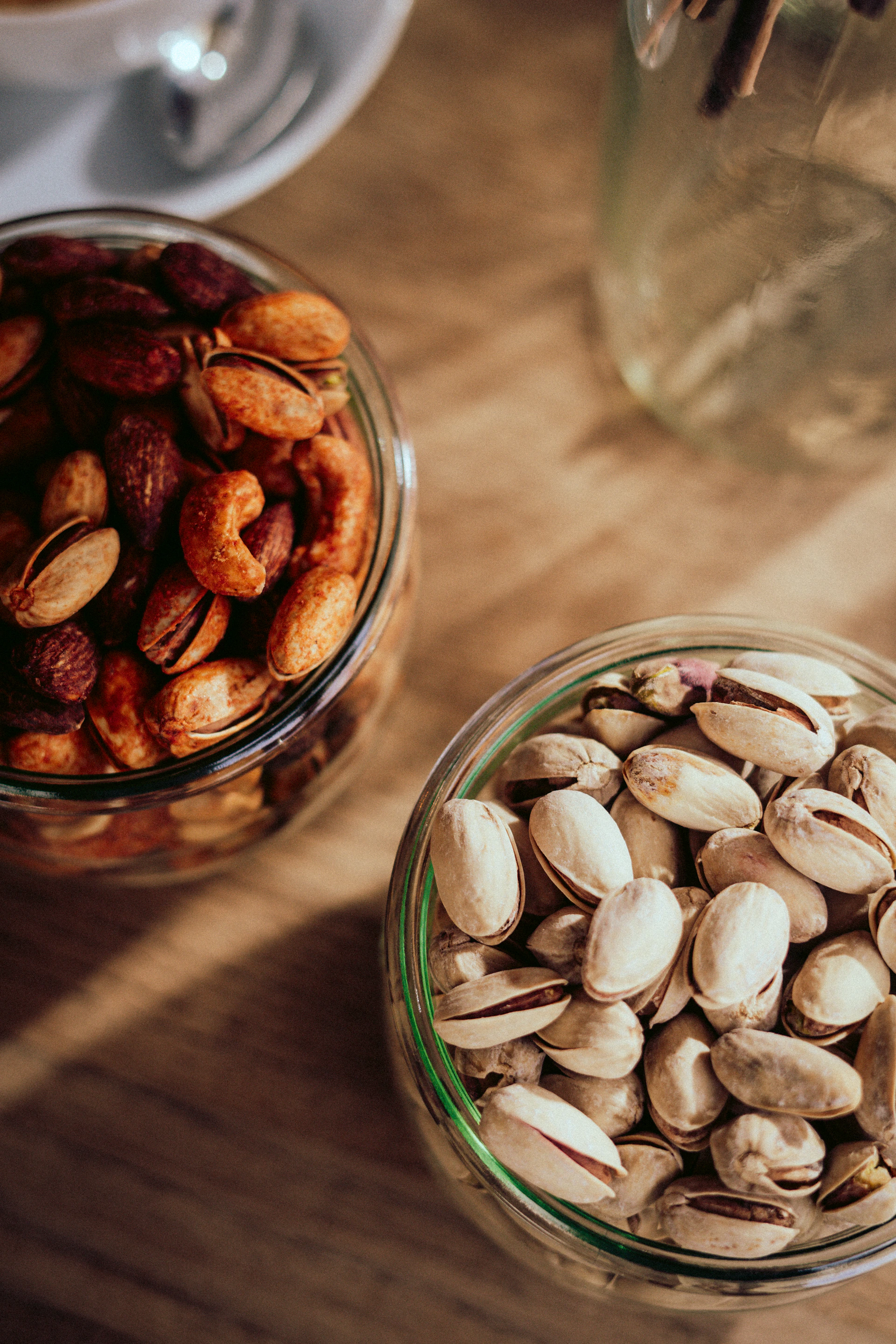 two glass bowls filled with nuts on top of a wooden table