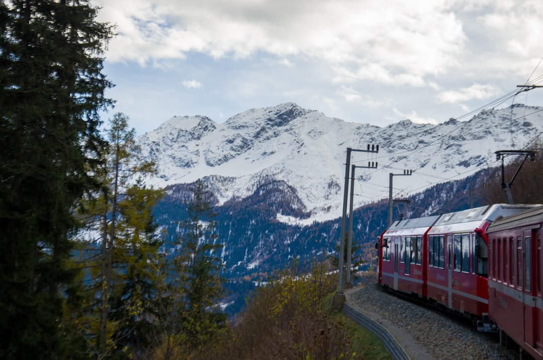 a red train traveling down train tracks next to a snow covered mountain,