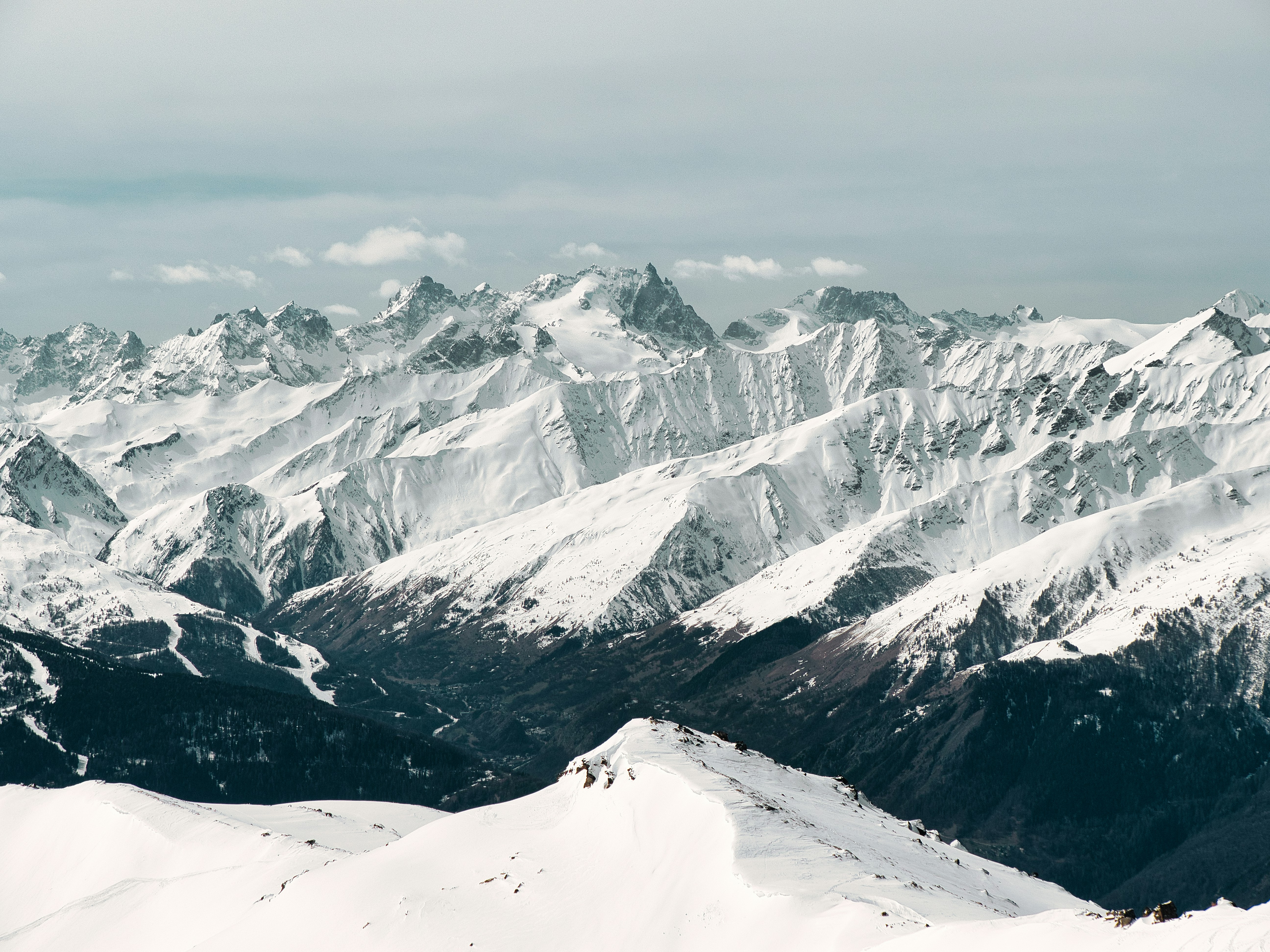 a mountain range covered in snow with a sky background