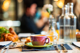a cup of coffee sits on a table with silverware