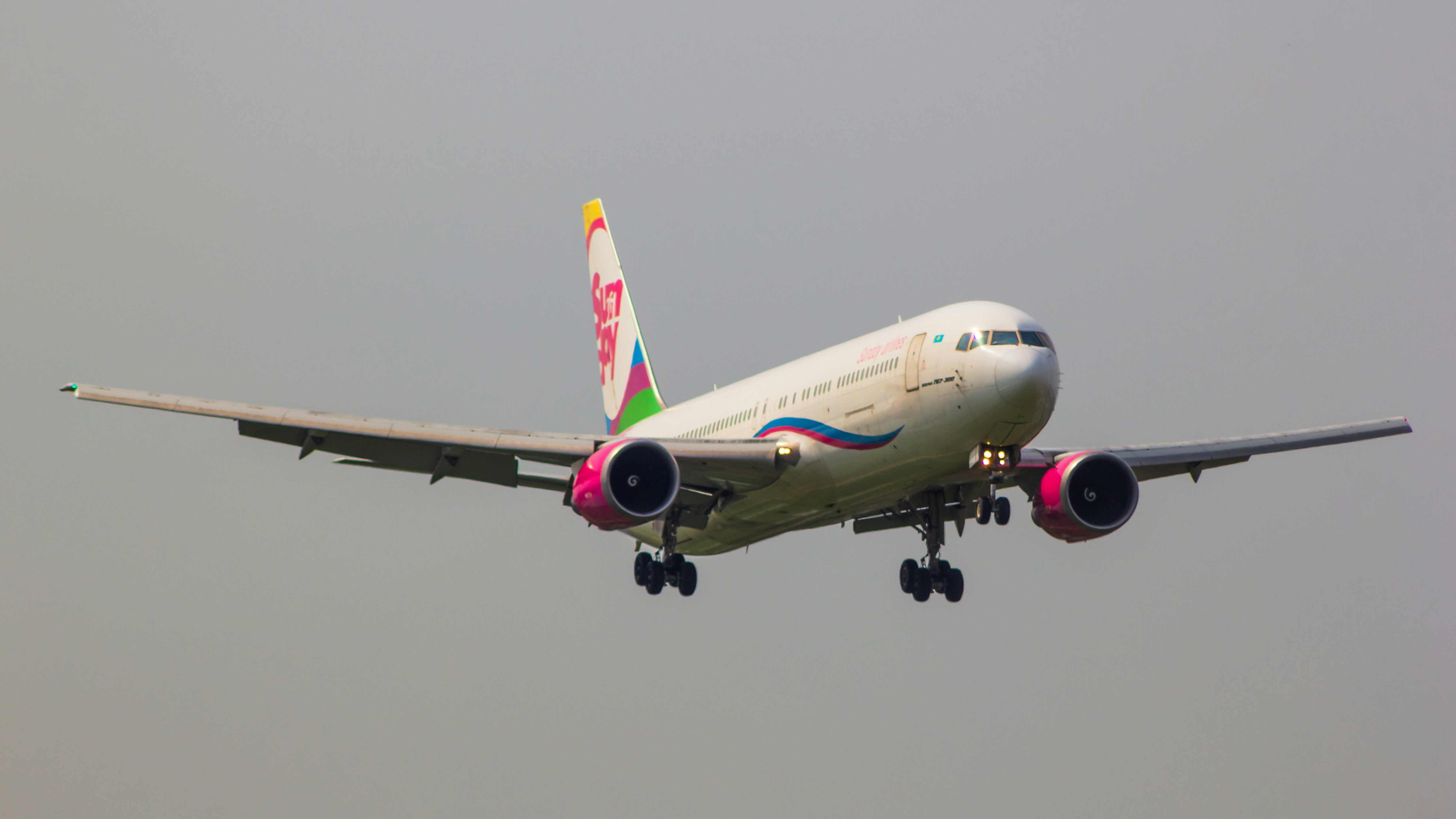 a large jetliner flying through a gray sky, Sunday Airlines Boeing 767-300ER