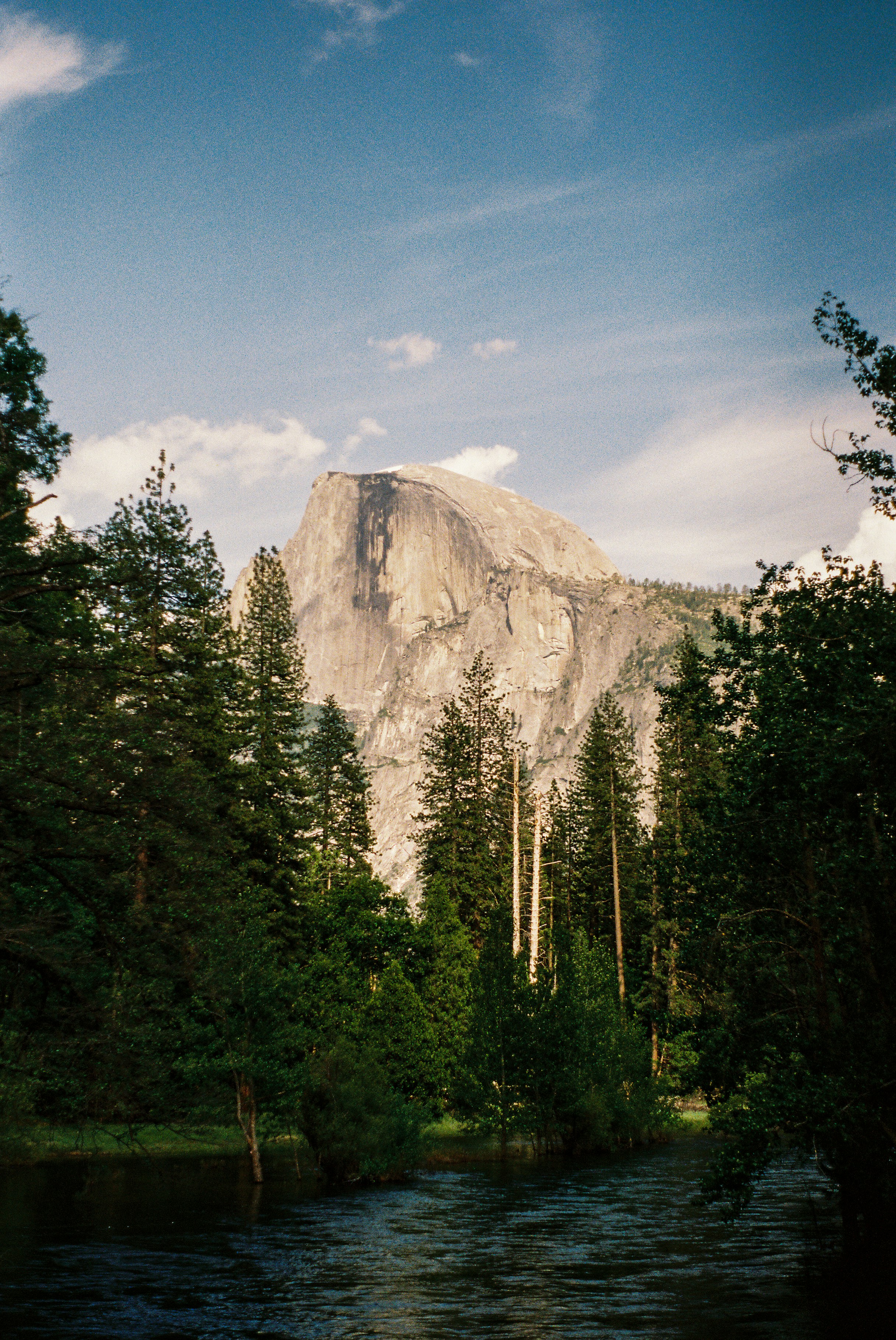 une rivière qui coule à travers une forêt à côté d’une haute montagne