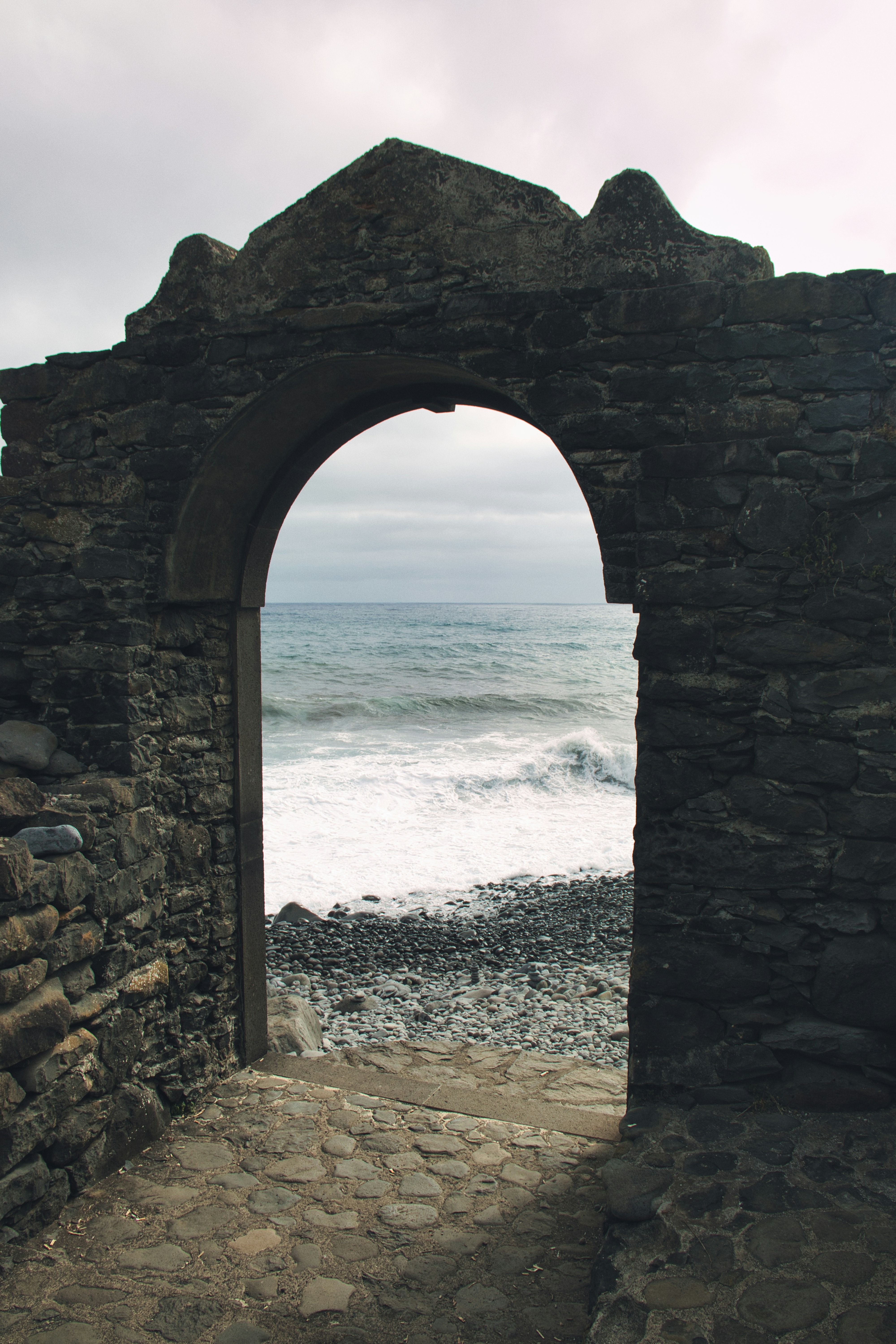 a stone arch with a view of the ocean