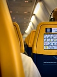 a yellow seat on an airplane with headphones on