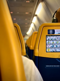 a yellow seat on an airplane with headphones on