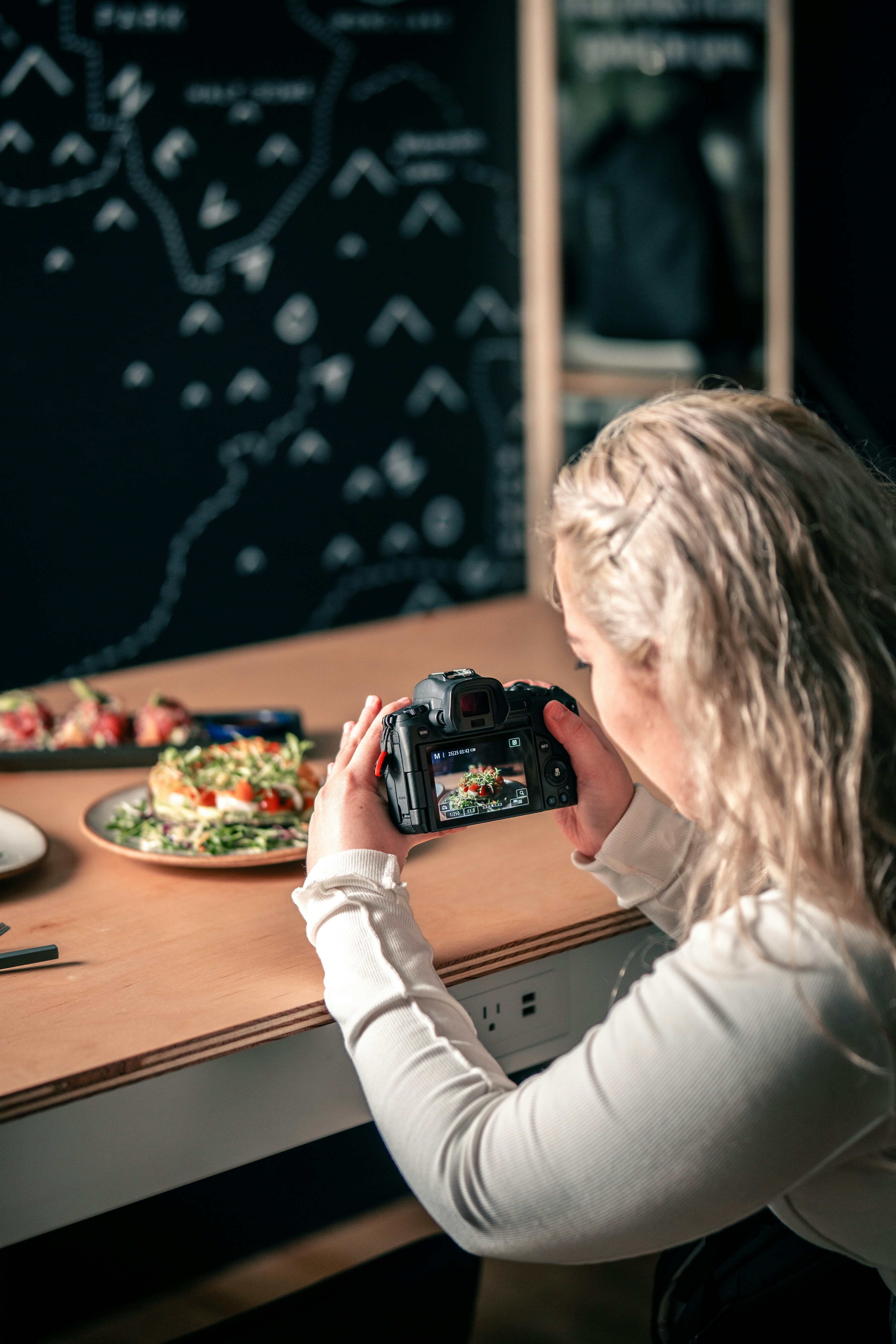 une femme assise à une table prenant une photo de nourriture