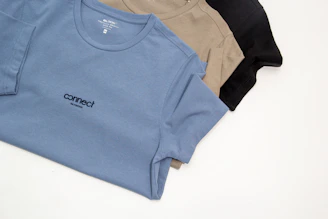 a group of three t - shirts sitting on top of a white table