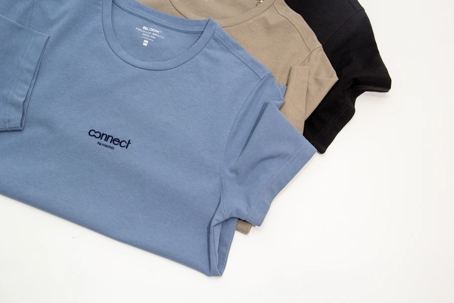 a group of three t - shirts sitting on top of a white table