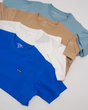 a group of four t - shirts sitting on top of a white table