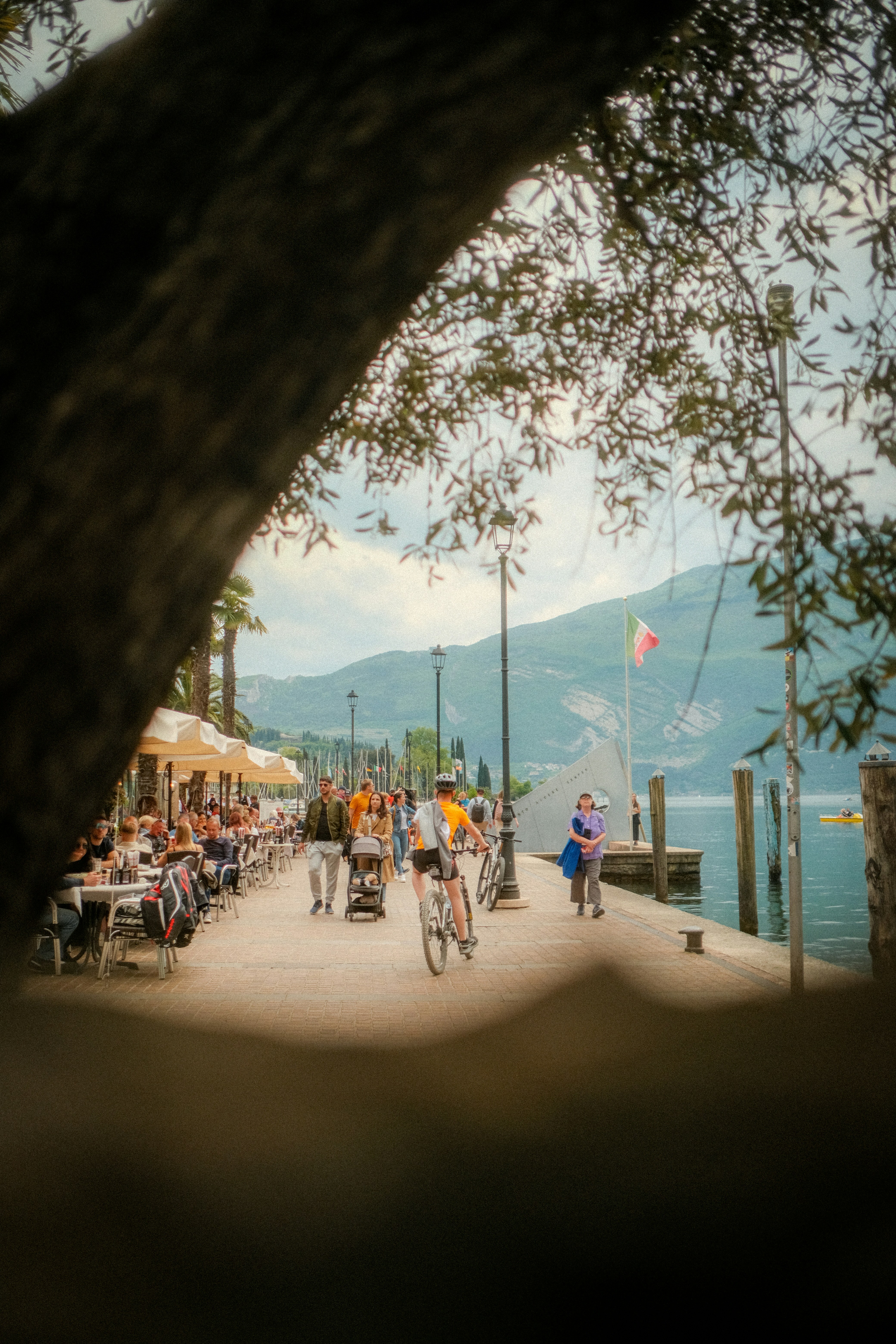 a group of people riding bikes down a street next to a body of water