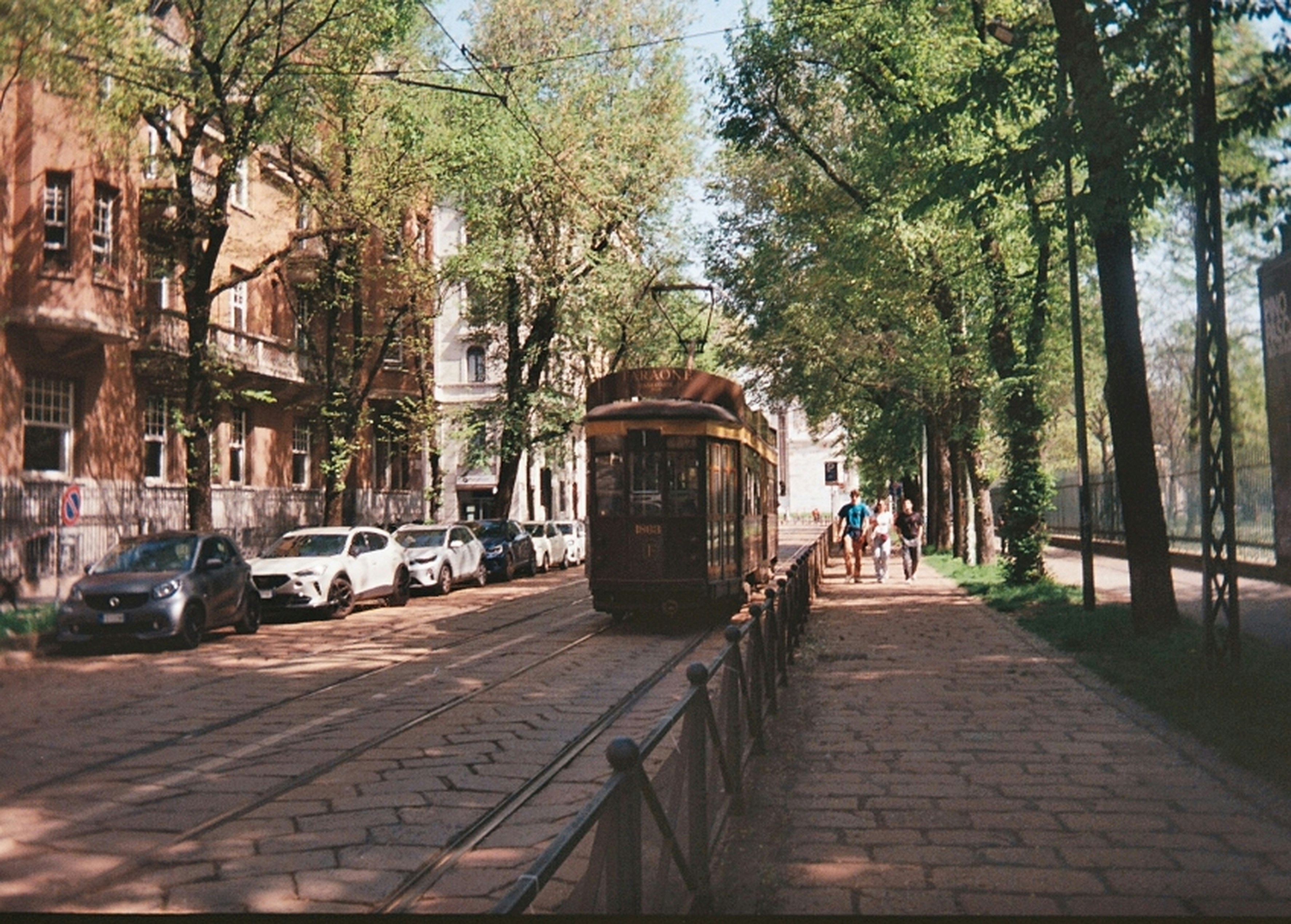 a trolley car traveling down a street next to parked cars