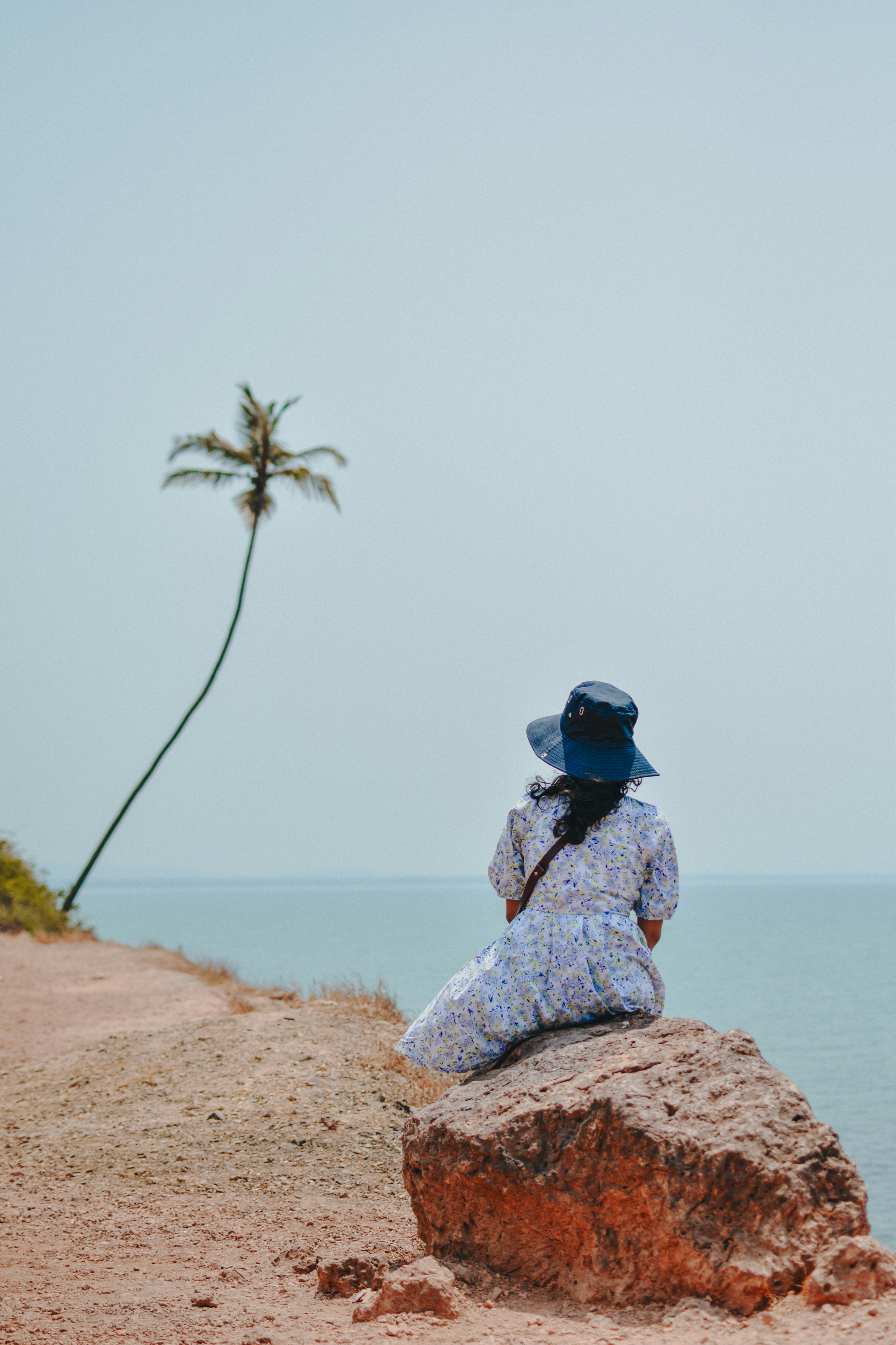 A woman sitting on top of a rock near the ocean photo – Free Grey Image ...