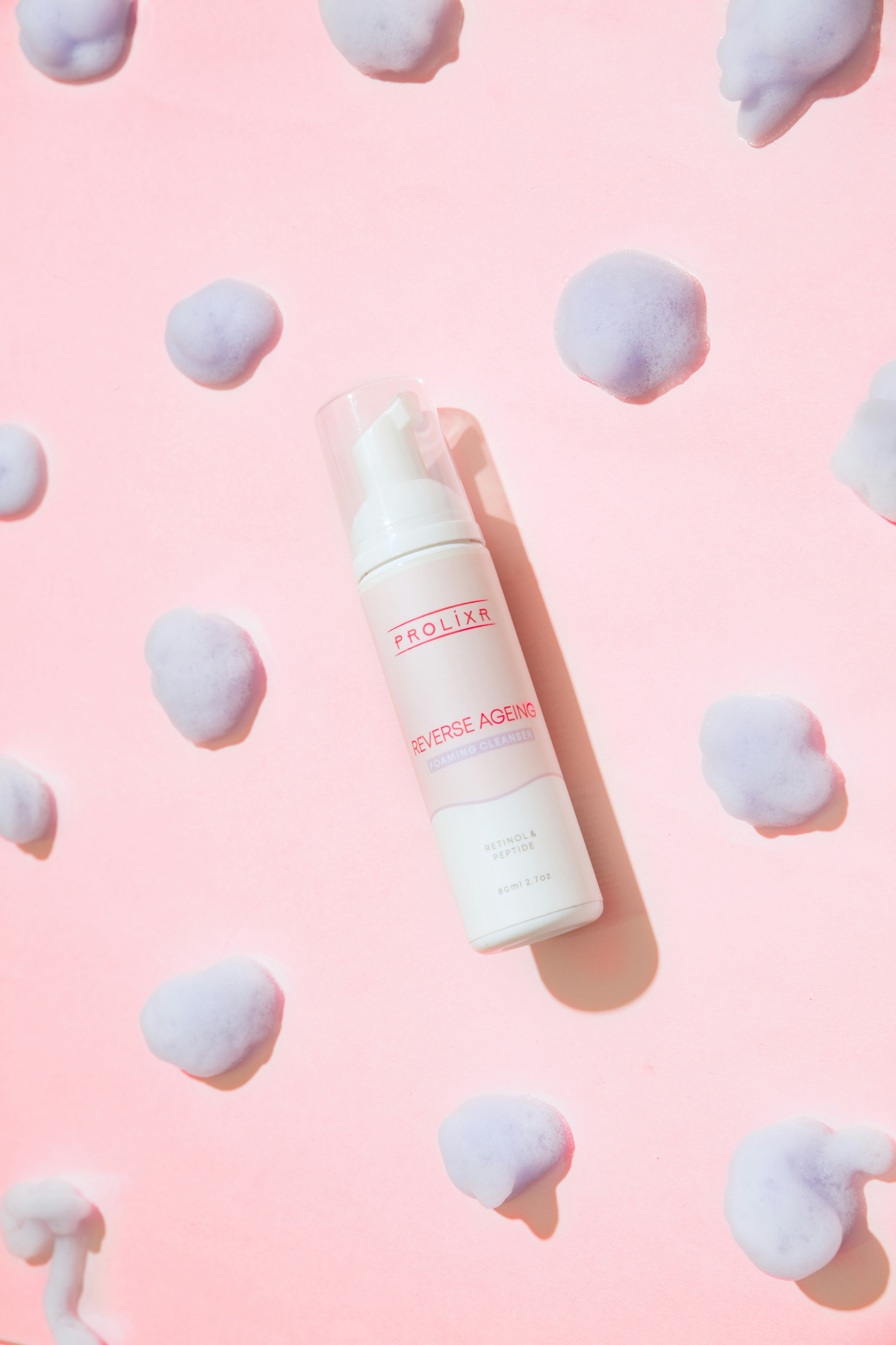 a bottle of lotion sitting on top of a pink surface