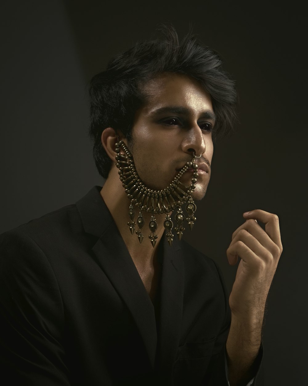  a man wearing a black suit and a gold necklace
