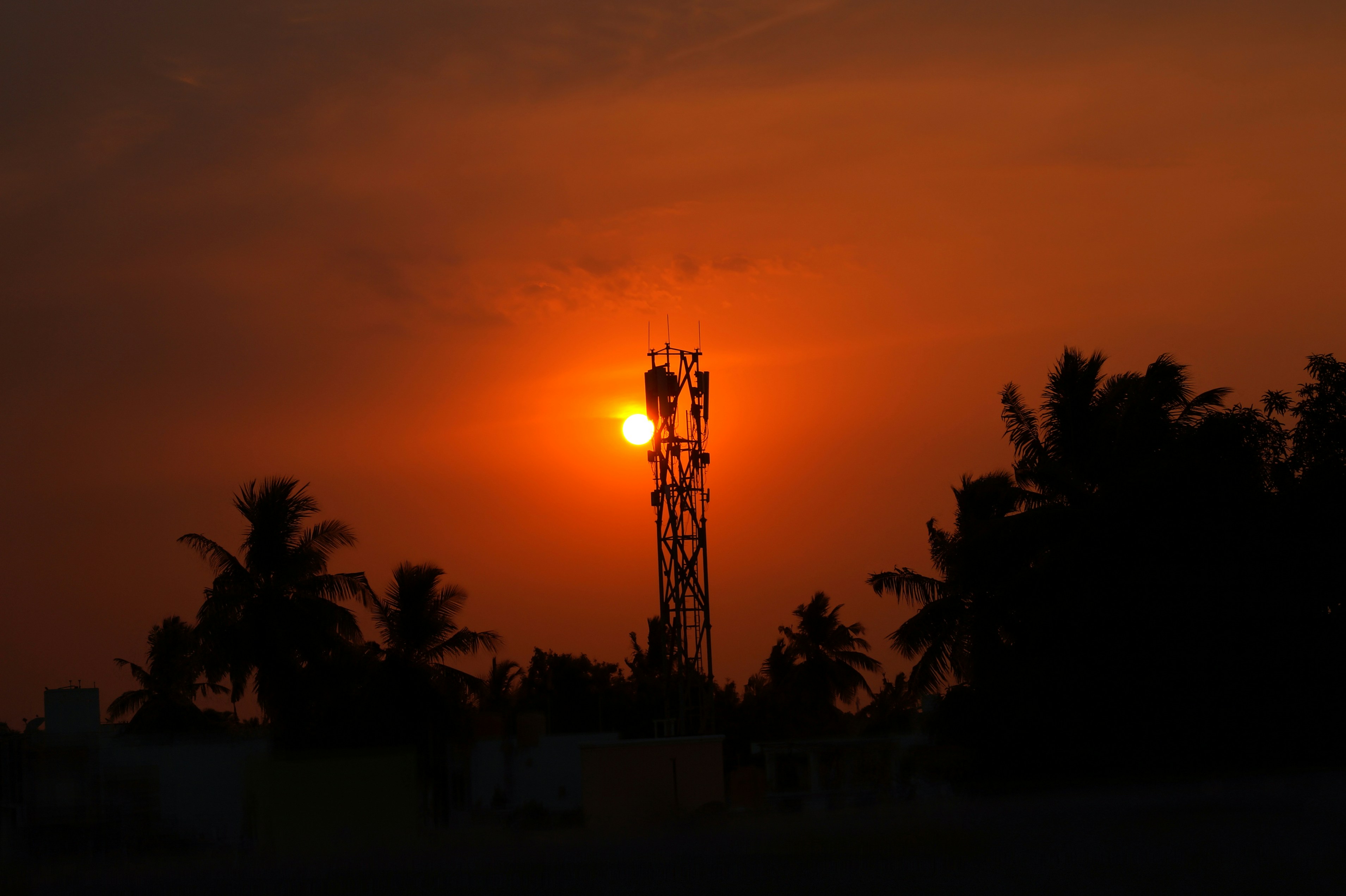 Il sole sta tramontando dietro una torre con un telefono cellulare