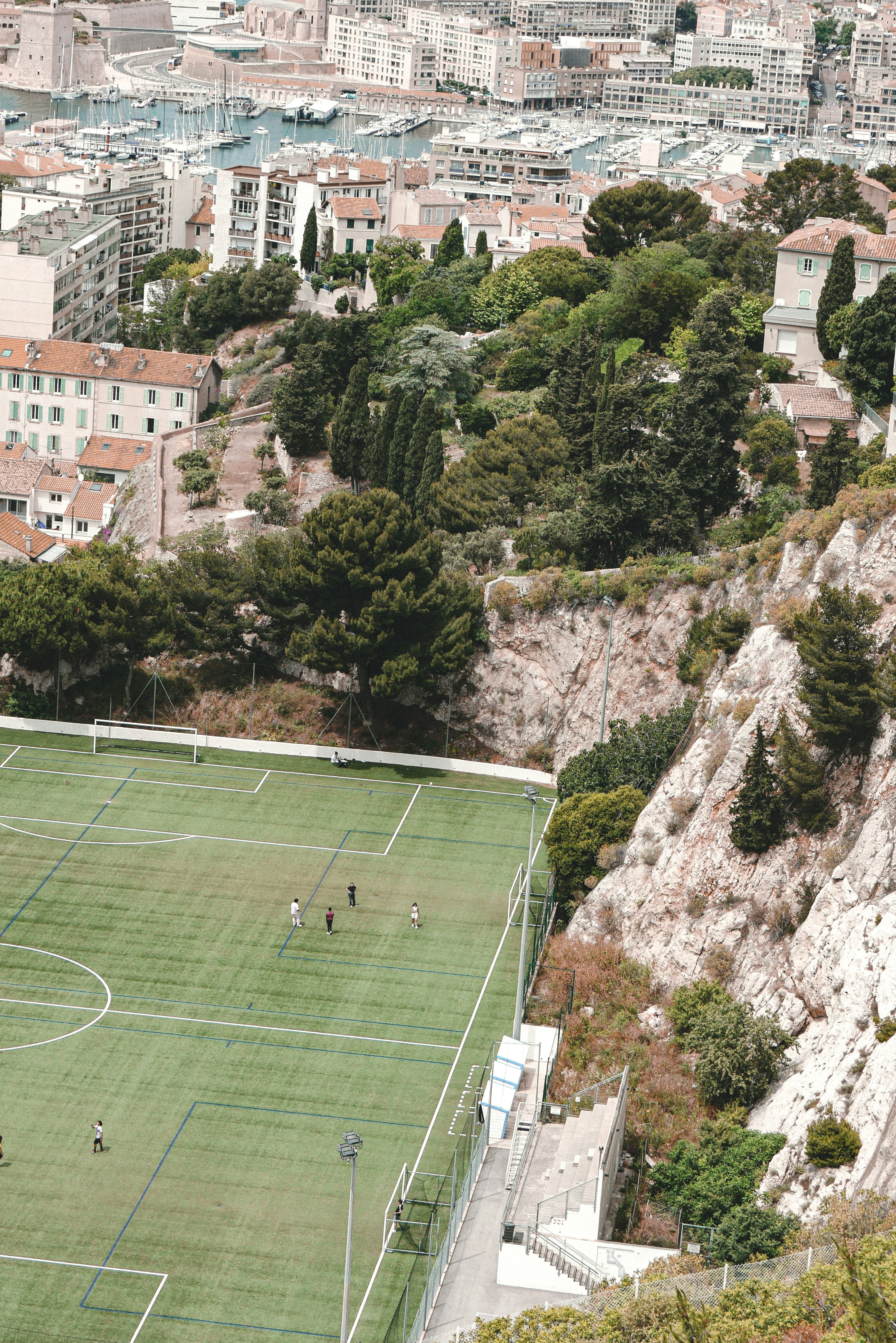 Campo de futebol visto do alto junto a uma cidade costeira