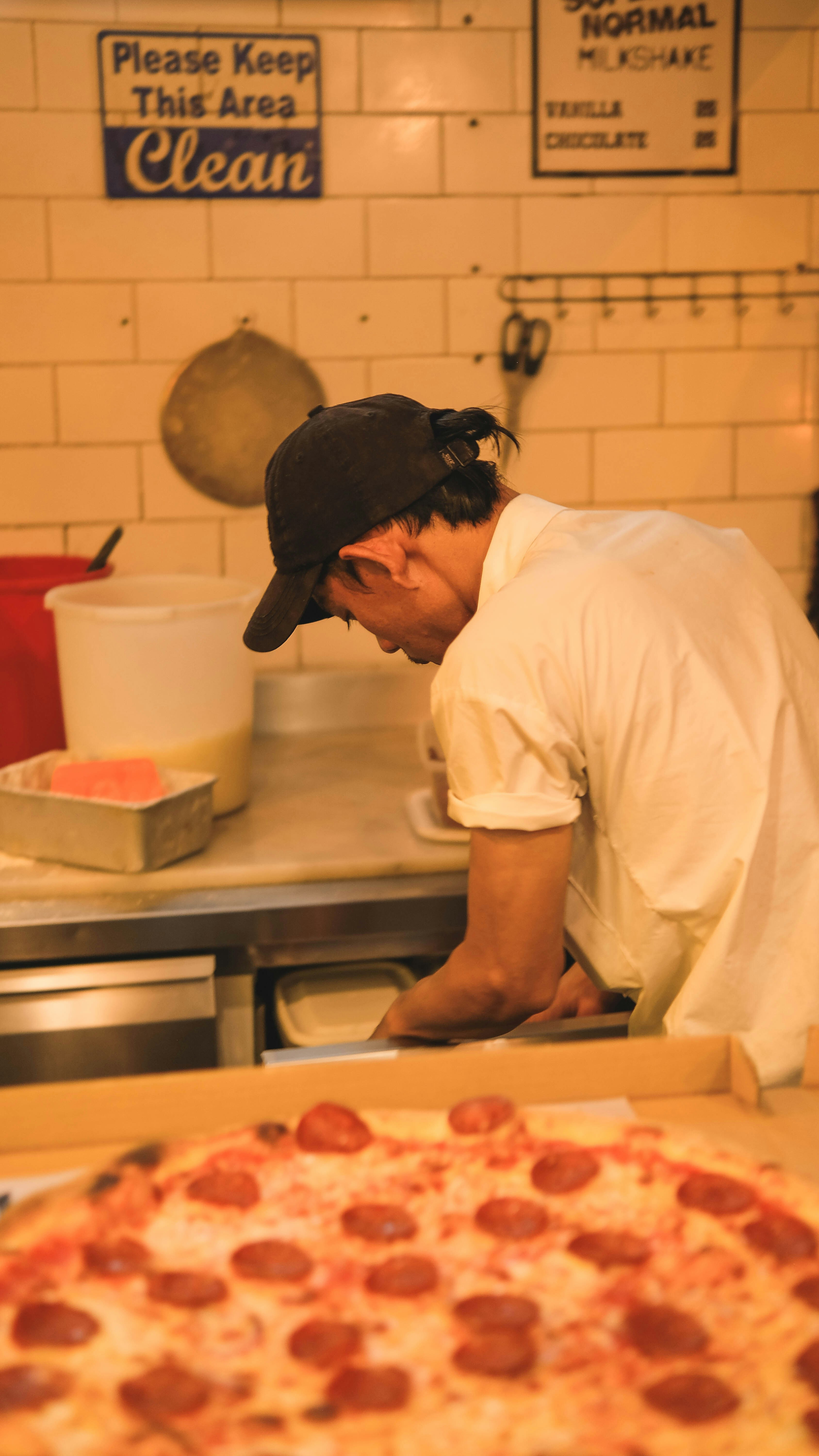 a man standing over a pizza in a kitchen