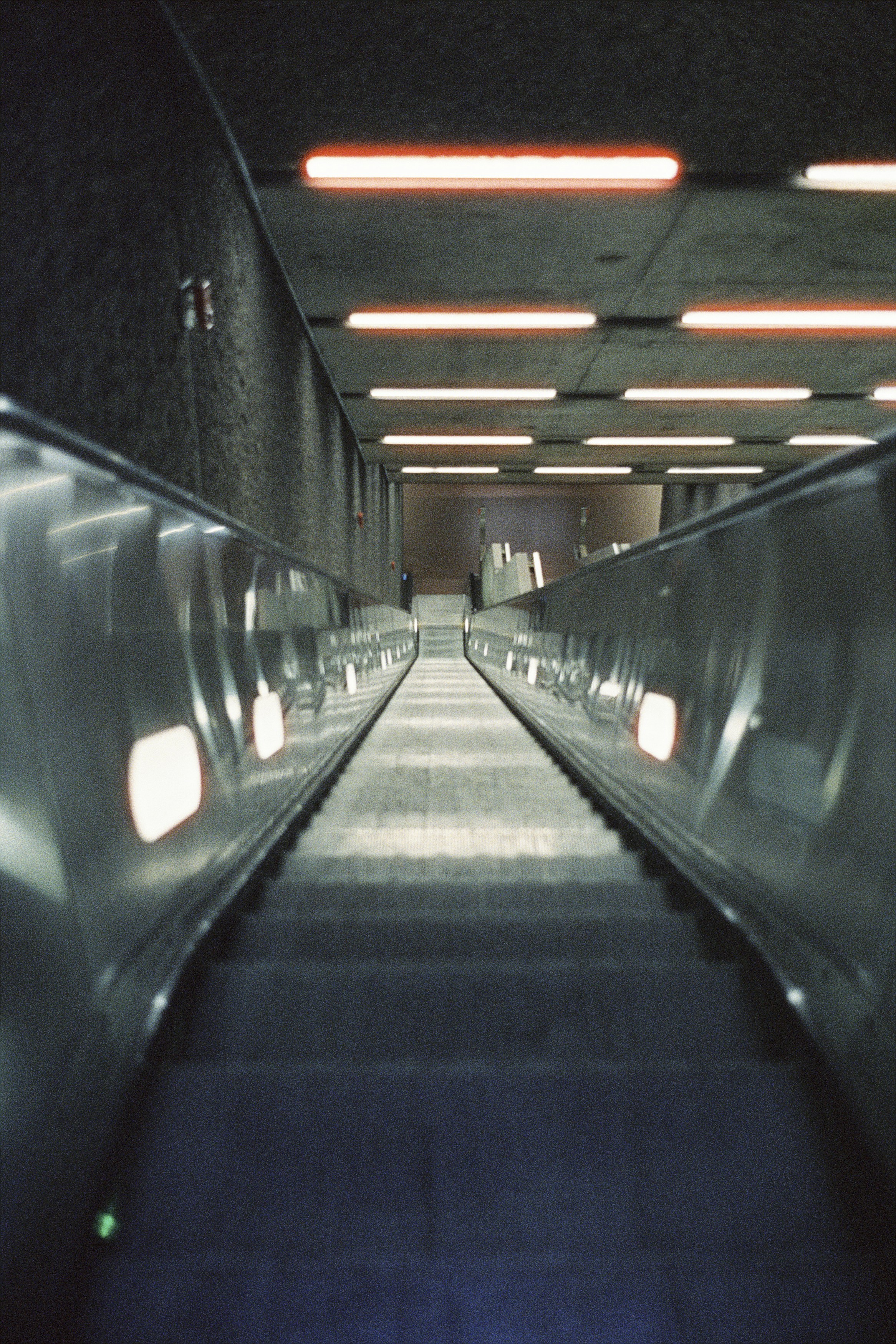 an empty subway station with lights on the ceiling