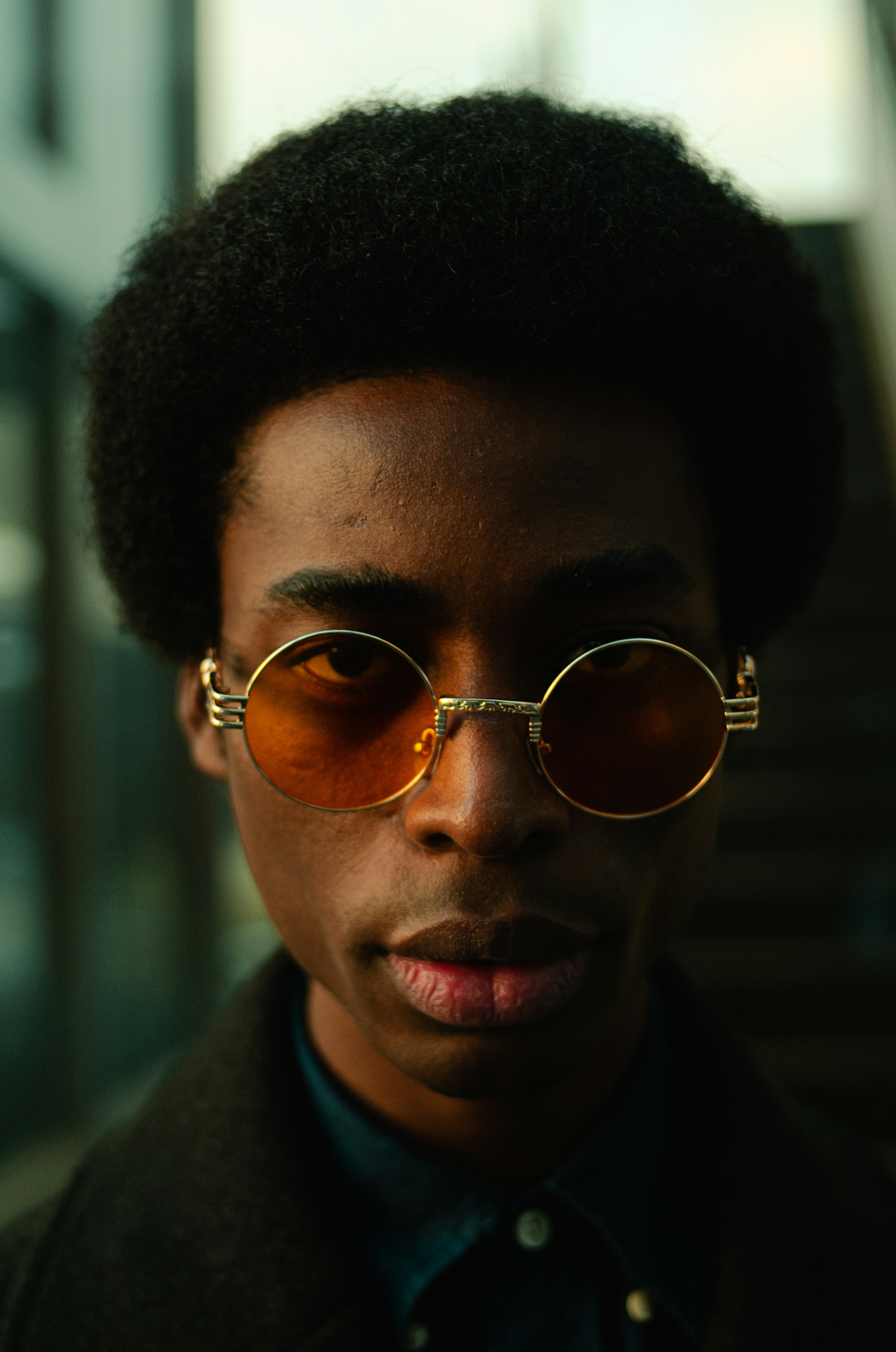a young man wearing a pair of round sunglasses