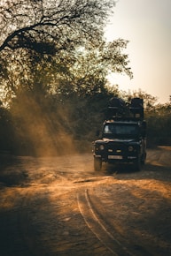 a truck driving down a dirt road next to a forest