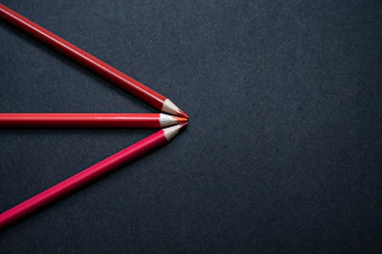 two red pencils sitting side by side on a black surface