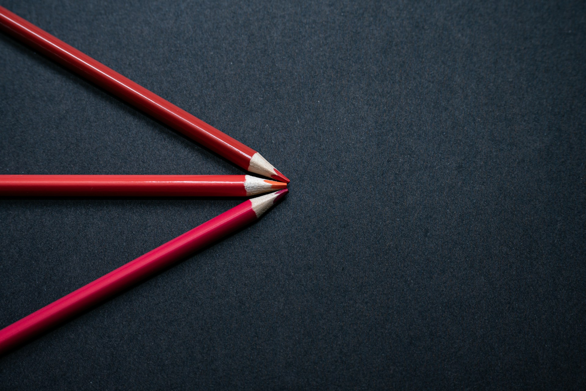 two red pencils sitting side by side on a black surface