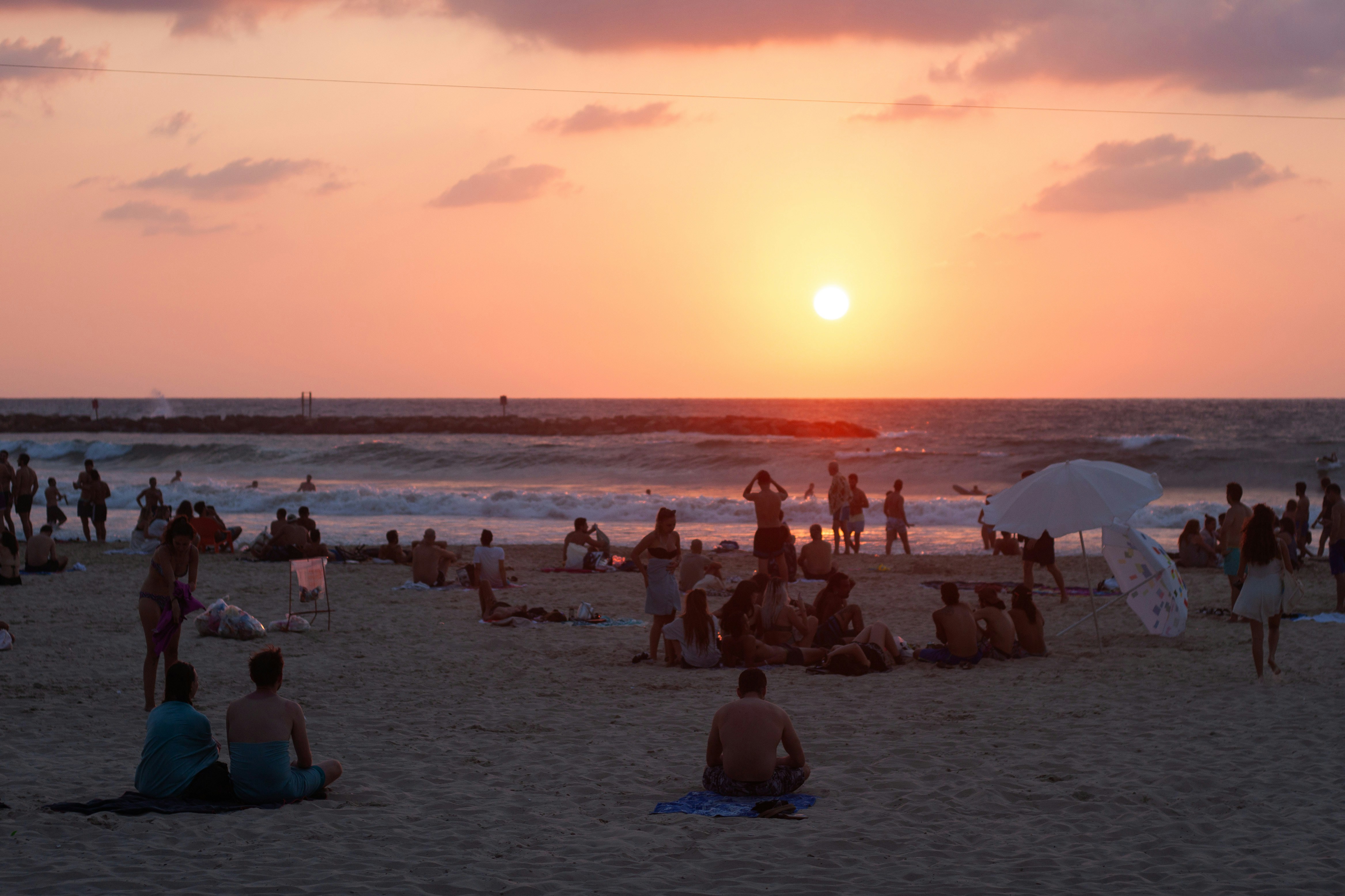 a group of people sitting on top of a sandy beach