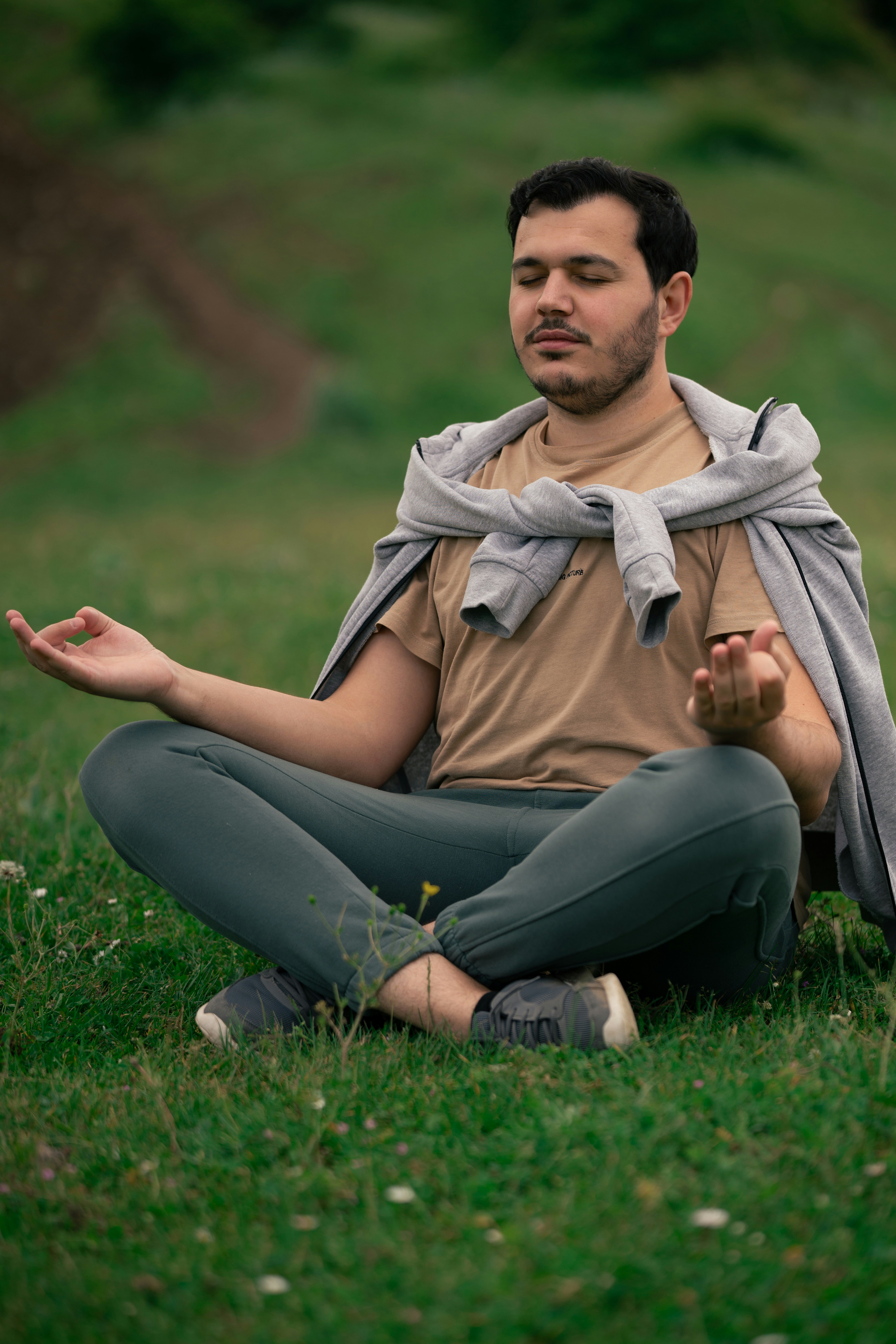 a man sitting in the grass doing yoga