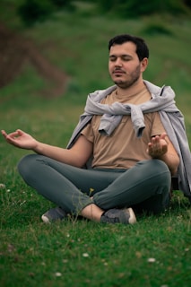 a man sitting in the grass doing yoga