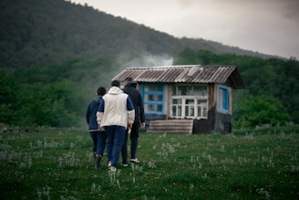 a group of people walking in front of a small cabin