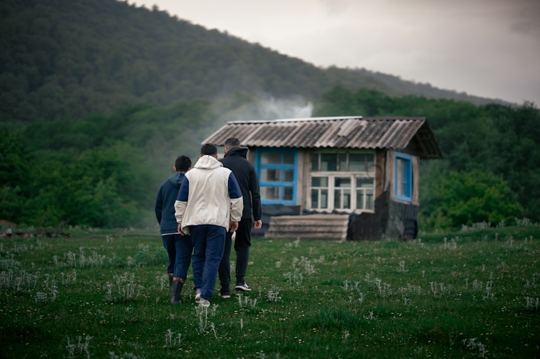 a group of people walking in front of a small cabin