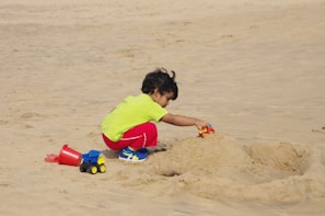 a little boy playing in the sand with a toy truck